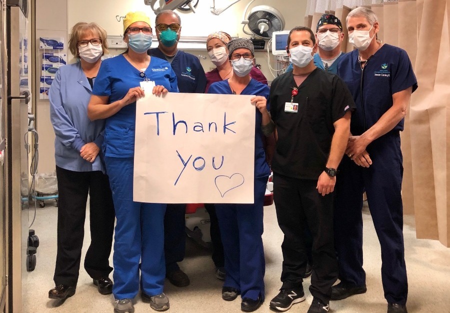 Caregivers say thank you. Group of caregivers in scrubs holding Thank You sign