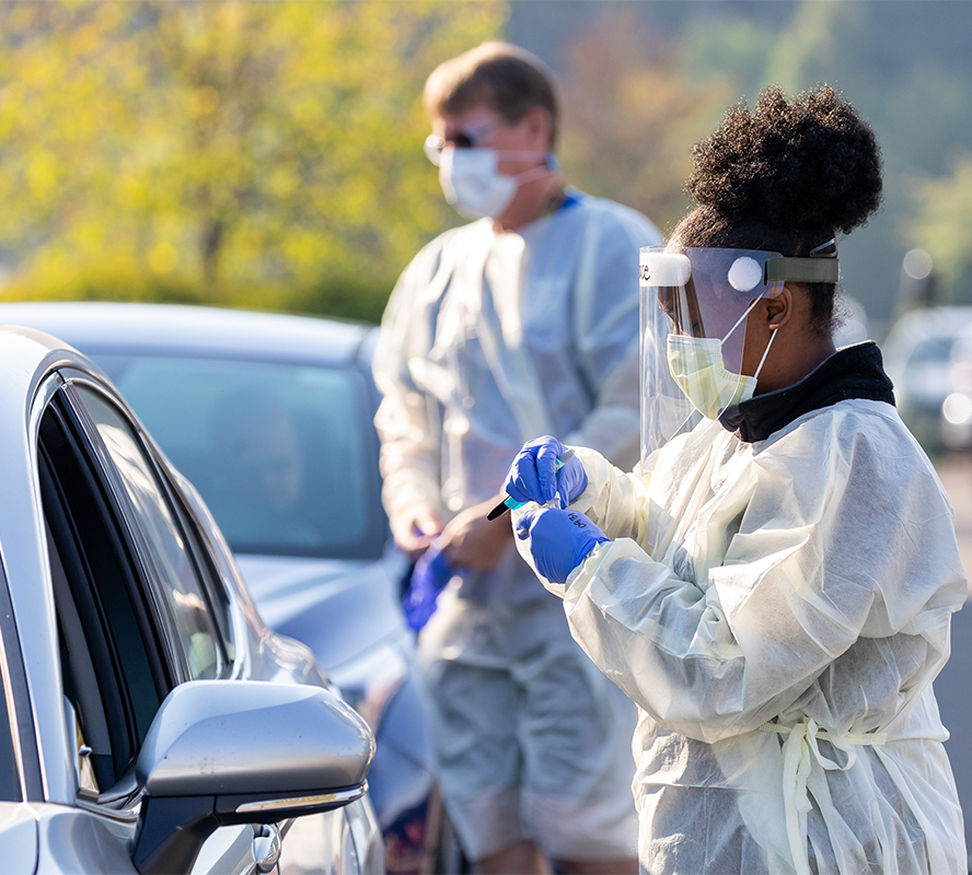 Vaccine Drive Thru Clinic Masked caregiver talks to patient in vehicle