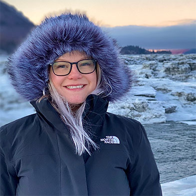 Brittany Lovelace in furry hooded parka near icy coastline