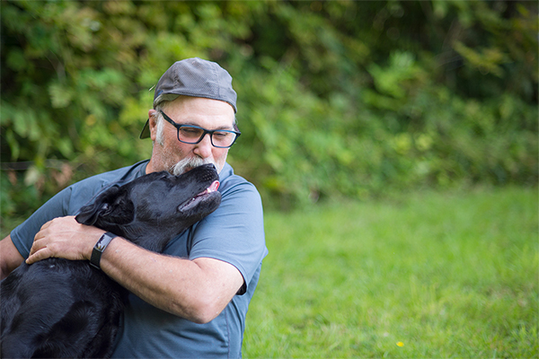 George Schlosser hugs and kisses black lab on the nose