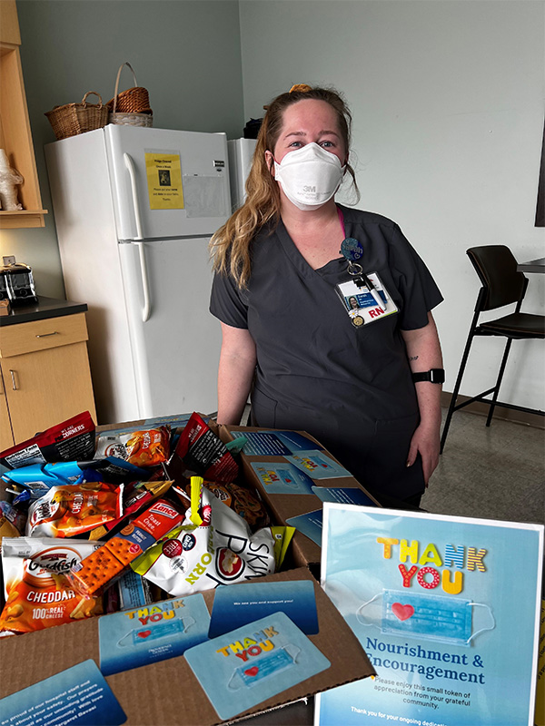 Nurse with Nourishment & Encouragement Box Masked nurse poses with box full of treats