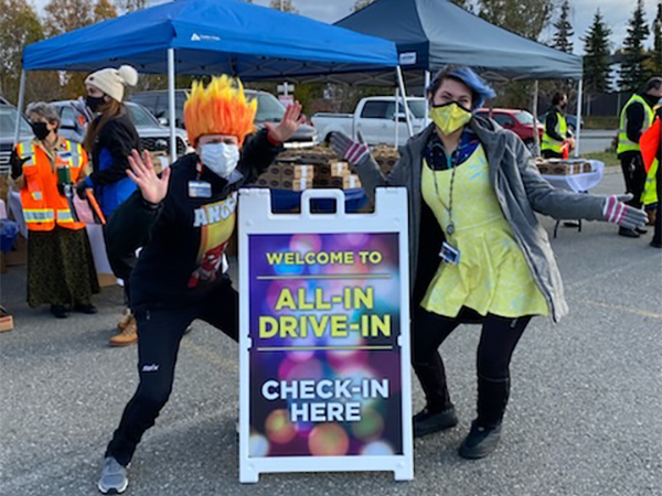 Two masked volunteers welcoming guests at check in.