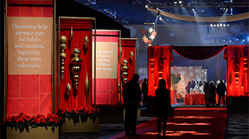 Lit hallway decorated with poinsettias leading into gala event