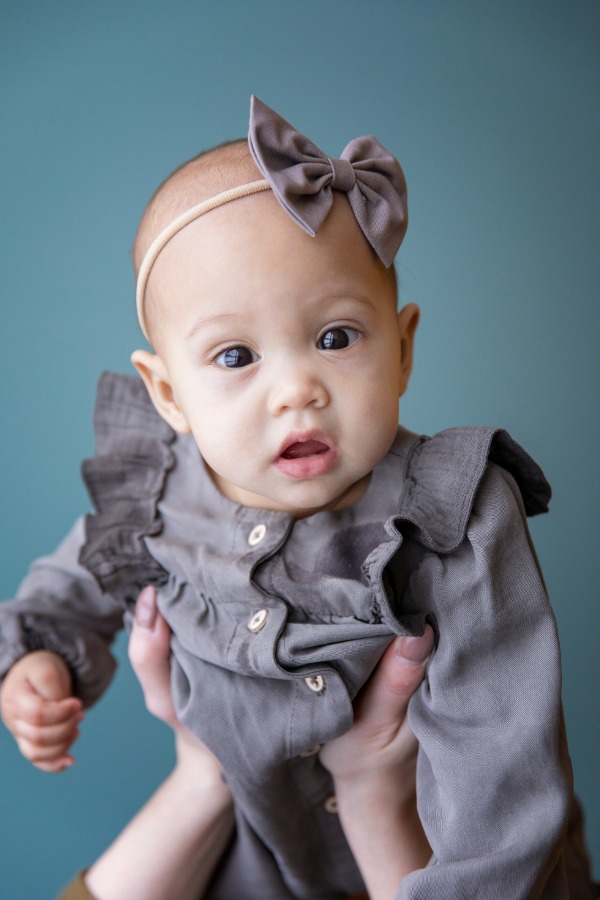 Baby Delilah wearing a grey dress and grey bow