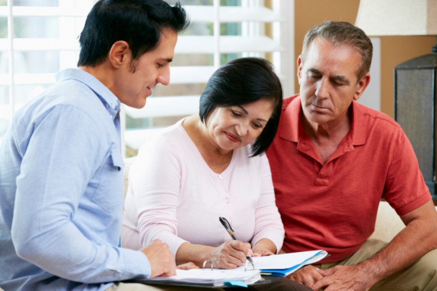 Planned Giving Woman signing documents while husband and financial expert observe