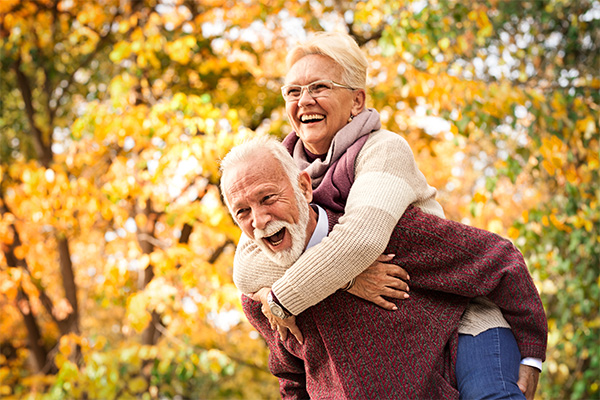 Elderly man gives elderly woman a piggy-back ride