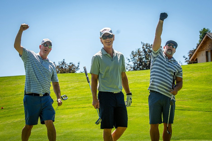 Three golfers with fists pumping in air.