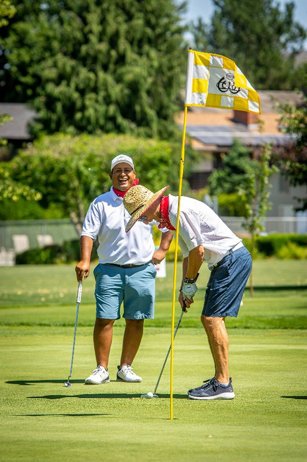 Golfer putting while another looks on.