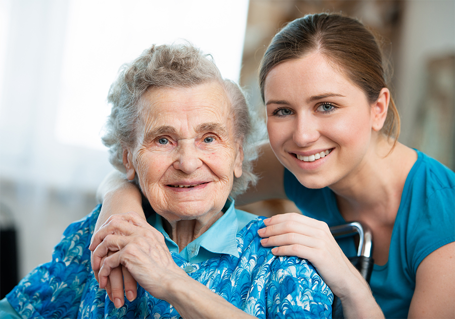 Patient and Caregiver Caregiver standing behind elderly patient with arms on shoulders