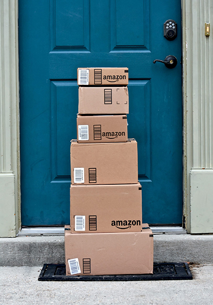 A tower of Amazon packages in front of a front door.